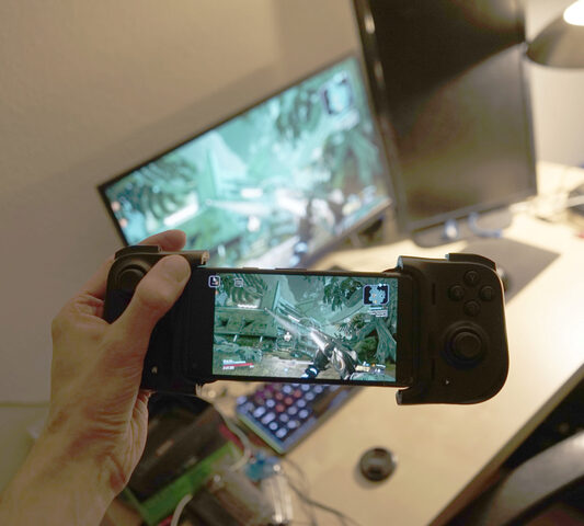 Un smartphone avec une manette, devant le PC qu'il contrôle, avec le jeu Borderlands 3.